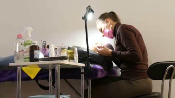 Kamenskoye, Ukrajina - 11. listopadu 2019: Kosmetický salon, kde se konají různé kosmetické procedury. Kosmetička provádí laminaci a hojení řas ke klientovi. — Stock video