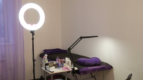 Kamenskoye, Ukraine - November 11, 2019: Cosmetic parlor where various beauty procedures are held. A special lamp for the face and various preparations on table in front of the couch — Stock Video
