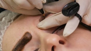 Mikropatenli kaş dövmesi, kalıcı makyaj. Eldivenlerde uzman, özel bir iğne kullanarak, cilde pigmenti enjekte eder ve kaş boyalarını saç tekniği ile lekeler, onları doğal, yakın çekim görüntü yapar.