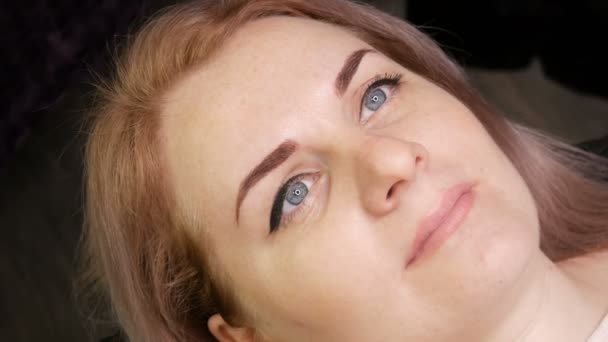 Beau visage de jeune femme avec maquillage permanent des sourcils et des flèches peintes sur les yeux nus — Video