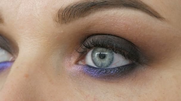 Beautiful expensive stylish evening make-up smoky eyes of unusual gray and blue shade of eyeshadow. Beautiful female blue eyes close up view and special eye makeup brush — Stock Video