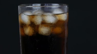 Siyah bir arka planda buz ile şeffaf bir uzun cam soğuk kola kabarcıkları görünümü yakın.