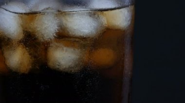 Siyah bir arka planda buz ile şeffaf bir uzun cam soğuk kola kabarcıkları görünümü yakın.