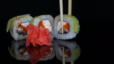 Yeşil Ejderha suşi rulo ve pembe zencefil. Somon, sebze ve avokado closeup suşi roll. Japonya Restoran Menü siyah bir arka plan ayna yüzeyinde. Studio Japon mutfağı