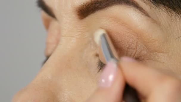 Maquiagem artista fazer maquiagem olho para mulher de meia-idade com olhos azuis. Maquilhagem. Retrato de close-up. Aplicar pó com escova — Vídeo de Stock