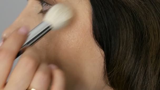 Make-up Artist Make-up mit Textmarker Concealer zu Frau mittleren Alters mit blauen Augen. Altersschminke. Nahaufnahme Porträt. Puder mit Pinsel auftragen — Stockvideo