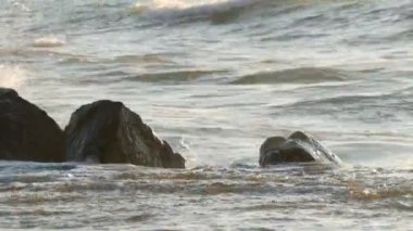 Güzel bir gün batımı ya da deniz üzerinde gün doğumu. Büyük güçlü dalgalar büyük kayalara çarpar. Denizde fırtına. Büyük dalgalar kayalık sahilde, beyaz köpükler suda kırılır. Karadeniz, Bulgaristan