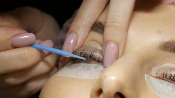 Professionelle Kosmetikerin reinigt Wimpern von der Farbe, die junge schöne Frau färbt — Stockvideo