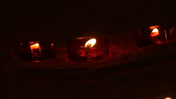 Bougies funéraires rouges rondes brûlant sur le sable dans un temple catholique. Lumière des bougies dans l'obscurité 