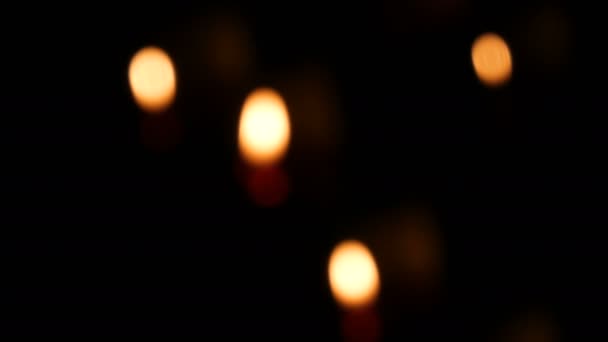 Red round burning funeral candles on sand in a catholic temple. Candlelight in dark defocus — Stock Video