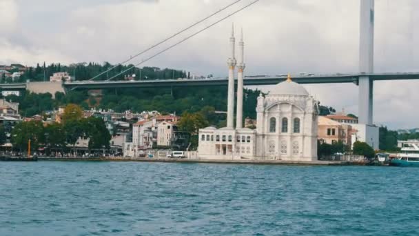 Yerleşim alanlarının arka planında güzel beyaz bir cami. Deniz manzarası ve oradan geçen bir turist teknesi. İstanbul, Türkiye — Stok video