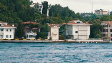 Deniz kıyısındaki yeşil tepelerdeki konut binalarının zengin lüks köşeleri yeşilliklerle çevrili. İstanbul, Türkiye 'den geçen bir tekneden görüntü