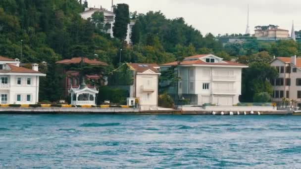 緑に囲まれた海岸沿いの緑豊かな丘の上の住宅ビルの豊かな高級4分の1 。渡し船、イスタンブール、トルコからの眺め — ストック動画