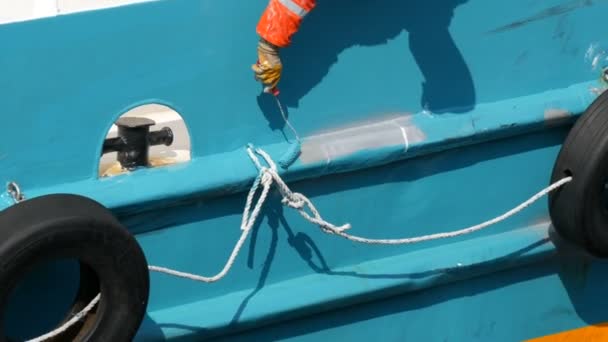 Mano de un hombre de un marinero pinta con una pintura con una popa de rodillo de barco o barco con pintura azul — Vídeos de Stock