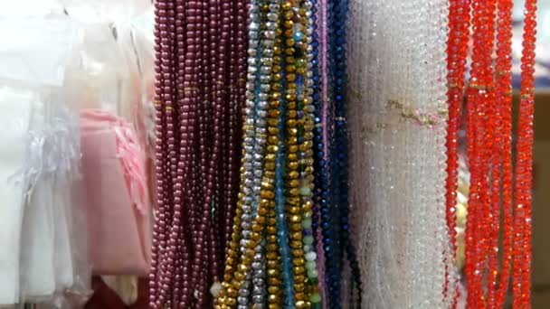 Különböző természetes kövekből származó színes gyöngyök lógnak az isztambuli ékszerüzletben. Színes gyöngyök nyakláncok divatos női nyilatkozat ékszerek, Női kéz választhat gyöngyök — Stock videók