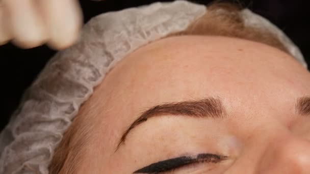 Mikroblästrande ögonbrynstatuering, permanent makeup. Master i handskar, med speciell nål, injicerar pigment i huden och färgar ögonbrynen med hjälp av hårteknik, vilket gör dem naturliga, närbild — Stockvideo