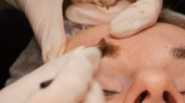 Mikropatenli saç kaşı. Kaş dövmesi ve kalıcı makyaj. Eldivenlerin ustası kaş derisine eşit miktarda pigment uygular.