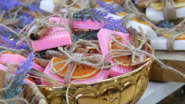 Sabão artesanal branco e rosa lindamente decorado com fatias de laranja secas, paus de canela e raminhos de lavanda no balcão da loja . — Vídeo de Stock