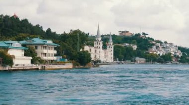 Deniz kıyısındaki yeşil tepelerdeki konut binalarının zengin lüks köşeleri yeşilliklerle çevrili. İstanbul, Türkiye 'den geçen bir tekneden görüntü