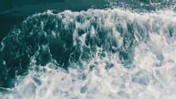 Belle eau de mer turquoise avec vagues et mousse blanche vue rapprochée sur le dessus. Le navire flotte sur la mer et coupe les vagues 