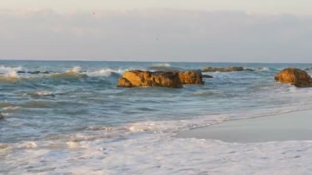 Beautiful sunset or sunrise over sea. Big strong waves crash into huge rocks. Storm at sea. Big waves break on the rocky shore, white foam on the water. Black Sea, Bulgaria — Stock Video