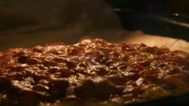 Pizzanın üzerindeki peynir fırının sıcaklığından erir. Lezzetli İtalyan pizza salamı ve fırında kızartılmış peynir. Yakın görüş.
