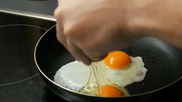 Male cook breaks eggs in pan for cooking fried eggs — Stock Video