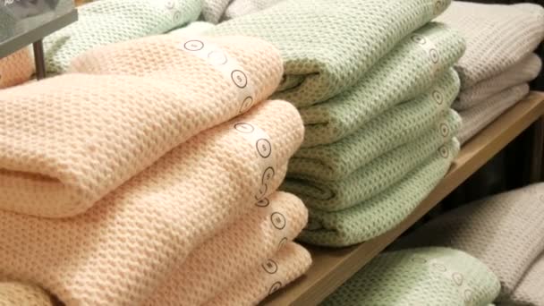 Beautiful warm womens knit sweaters of light color folded in a row on a shelf in clothing store — 비디오