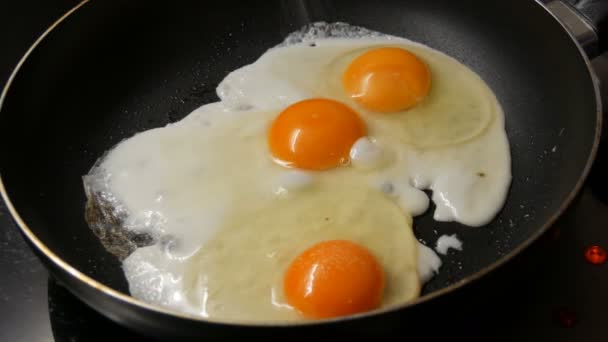 Крупный план яиц на сковороде, посыпанных солью — стоковое видео