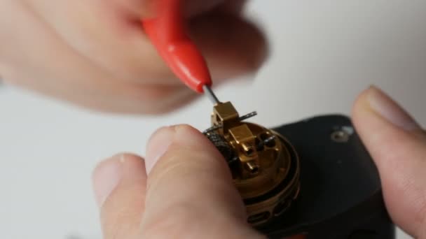 Un uomo inserisce una nuova bobina di ferro in una sigaretta elettronica marrone — Video Stock