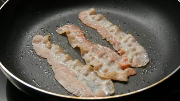 Fatias finas de bacon são fritas em óleo de girassol em panela quente com revestimento antiaderente — Vídeo de Stock