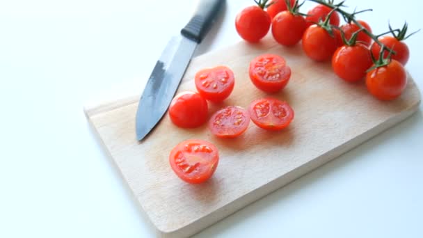 Όμορφα ζουμερά ώριμα κόκκινα ντοματίνια σε τσαμπί σε λευκό φόντο τραπεζιού και ξύλινη σανίδα κουζίνας και κομψό μαύρο μαχαίρι — Αρχείο Βίντεο