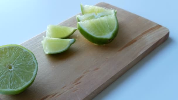 Ripe green lime sliced on kitchen wooden board on a white table background — Stock Video