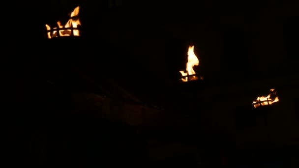 Fila de tres llamas de fuego en antorcha medieval encendido en oscuro sobre fondo negro — Vídeo de stock
