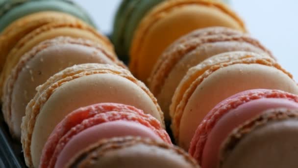 Разноцветные французские печенья макарон в специальном черном ящике на белом столе закрыть вид — стоковое видео