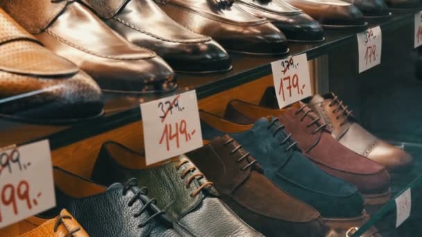 Estantes en la ventana de la tienda de zapatos con diferentes zapatos clásicos de cuero para hombre en varios colores con etiquetas de precios con ventas de descuento — Vídeos de Stock