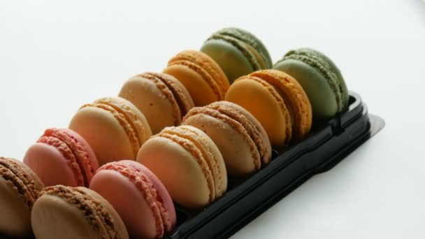 Veelkleurige franse koekjes macaron in een speciale zwarte doos op een witte tafel. Kleurrijke cake macaroon in een geschenkverpakking — Stockvideo
