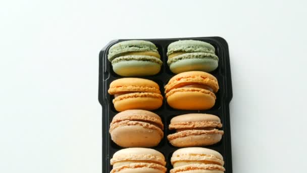 Galletas francesas multicolores macaron en una caja negra especial sobre mesa blanca vista superior — Vídeos de Stock