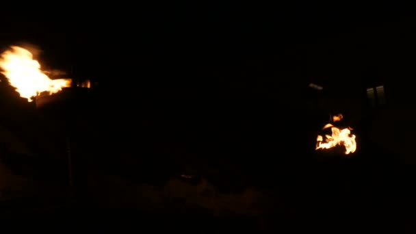 Fila de dos llamas de fuego en antorcha medieval encendido en oscuro sobre fondo negro — Vídeo de stock