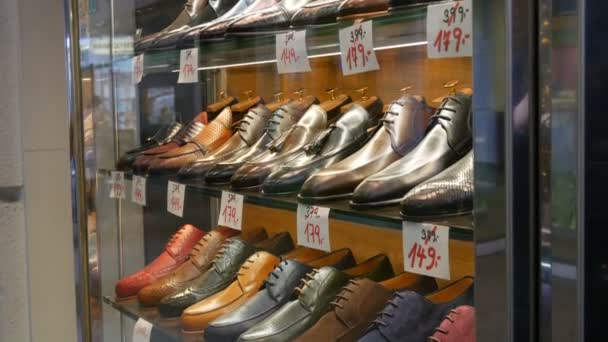 Estantes en la ventana de la tienda de zapatos con diferentes zapatos clásicos de cuero para hombre en varios colores con etiquetas de precios — Vídeos de Stock