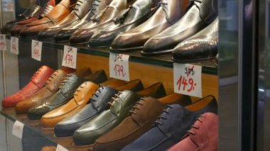Shelves in the window of shoe store with different classic leather mens shoes in various colors with price tags