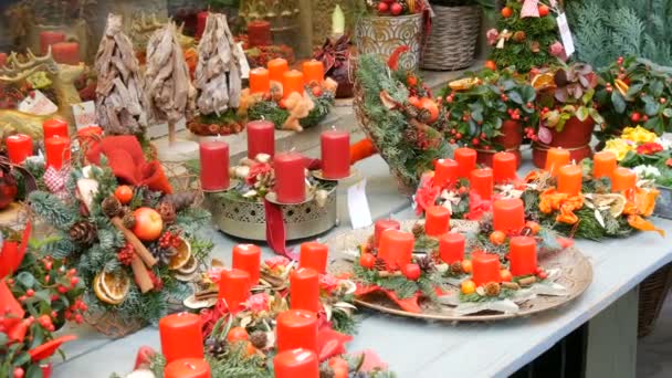 Bellamente decoradas composiciones de decoración de Navidad de velas de cera roja y guirnaldas en la ventana de la tienda — Vídeo de stock