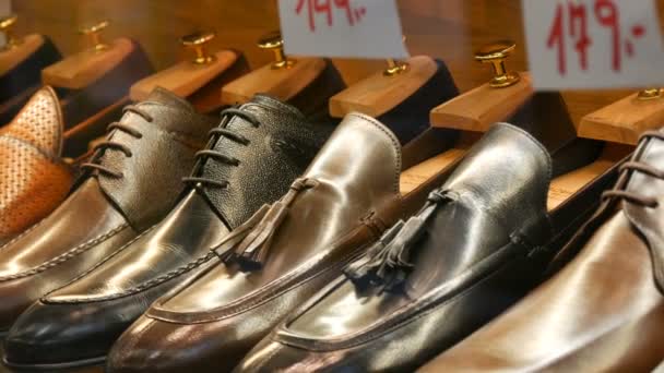 Estantes en la ventana de la tienda de zapatos con diferentes zapatos clásicos de cuero para hombre en varios colores con etiquetas de precios — Vídeos de Stock