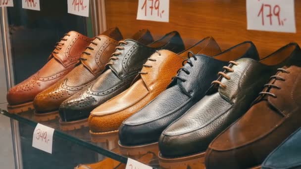 Shelves in the window of shoe store with different classic leather mens shoes in various colors with price tags with discount sales — 비디오