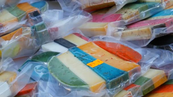 Interessante bunte Hartkuh- und Ziegenkäse in verschiedenen Geschmacksrichtungen im Lebensmittelladen auf dem Markt. Käse gelb, rot, lavendel, schwarz, grün. — Stockvideo