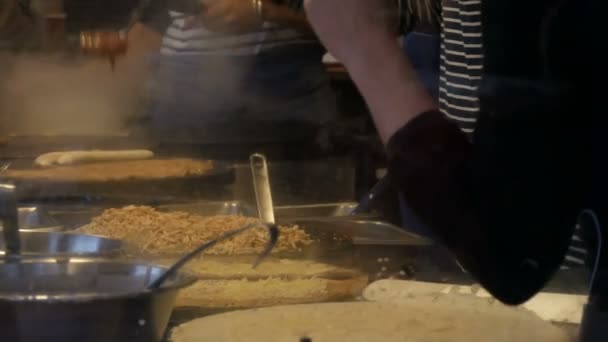 Mâinile bucătarilor în chioșc fast-food pregătesc omlete, clătite, tăiței și alte feluri de mâncare delicioase. Vedere laterală a femeilor și bărbaților gătește patru mâini — Videoclip de stoc