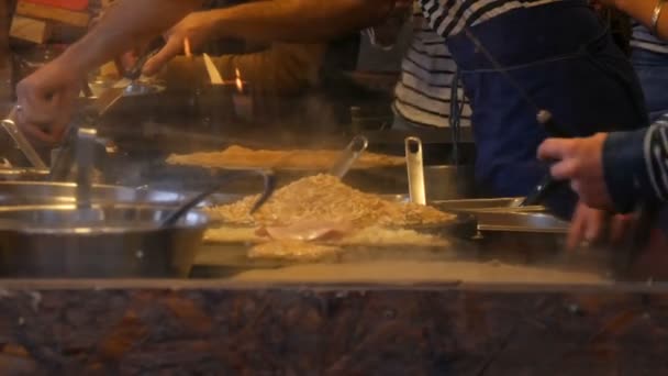 Mâinile bucătarilor în chioșc fast-food pregătesc omlete, clătite, tăiței și alte feluri de mâncare delicioase. Vedere laterală a femeilor și bărbaților gătește patru mâini — Videoclip de stoc