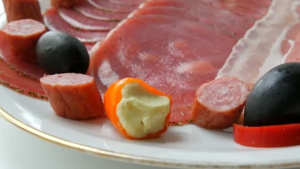 Fatias de carne e salsicha no prato ao lado de azeitonas pretas, páprica com queijo e salsichas de caça. Placa de carne curada — Vídeo de Stock