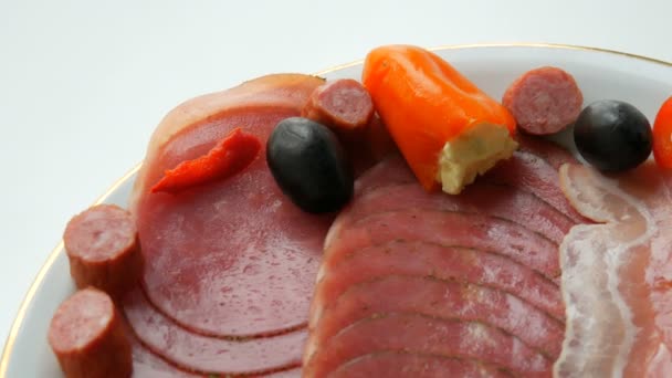 Meat and sausage slices on plate next to black olives, paprika with cheese and hunting sausages. Salami and sliced ham. Arranged dried meat in restaurant. Appetizing. Cured meat plate — 비디오