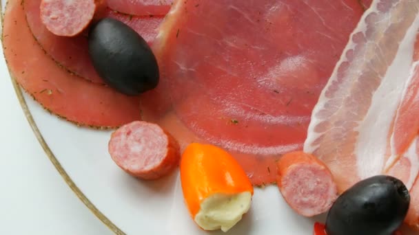 Meat and sausage slices on plate next to black olives, paprika with cheese and hunting sausages. Salami and sliced ham. Arranged dried meat in restaurant. Appetizing. Cured meat plate — 비디오